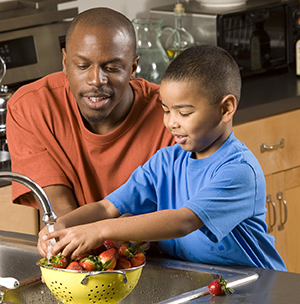 Un hombre y un niño lavan fresas en el fregadero.