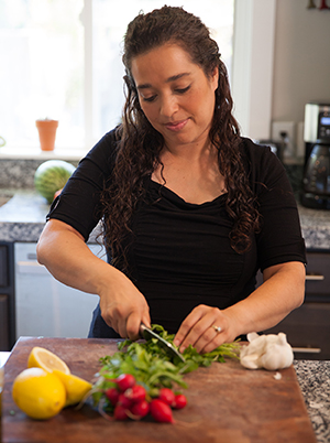 Mujer picando verduras frescas en la cocina.