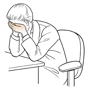 Mujer sentada ante un escritorio haciendo un ejercicio de cubrirse los ojos con las manos.